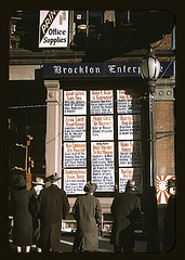 Men and a woman reading headlines posted in st...
