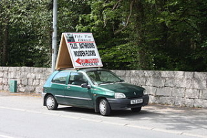 Car with sign on roof is early example of mobile advertising.